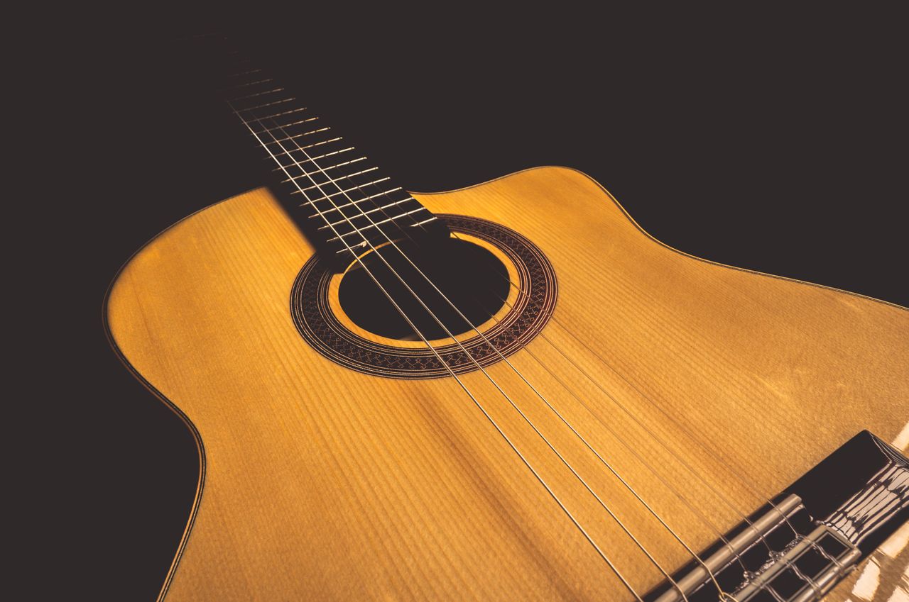 Services A beautifully detailed close-up of an acoustic guitar with warm lighting, emphasizing craftsmanship.