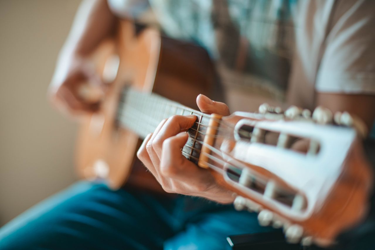 Services A person playing an acoustic guitar focusing on hand fretboard positioning.