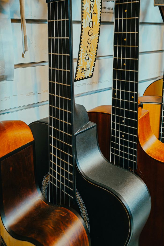 Home Multiple classical guitars on display in a music store, showcasing different wood finishes and intricate details.
