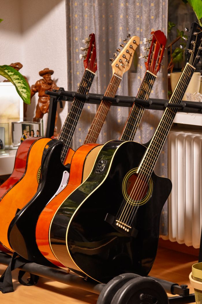 Services A variety of acoustic guitars on a stand, showcasing their vibrant colors and detailed craftsmanship.