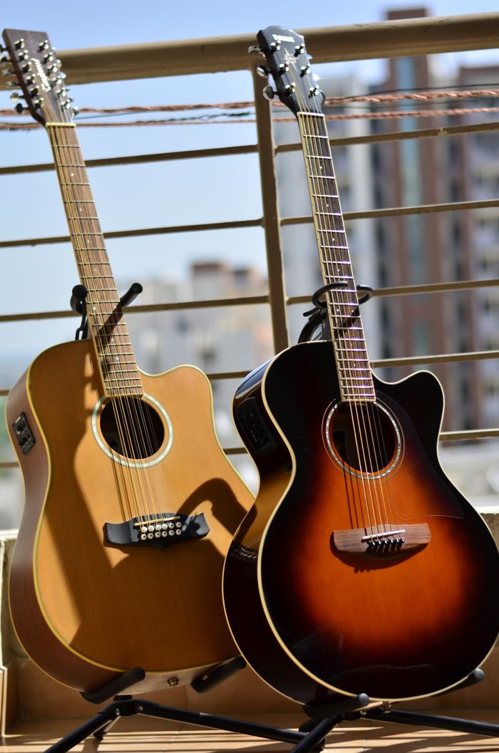 Contact View of beige and black brown new acoustic guitars on supports leaned to fence in sunlight